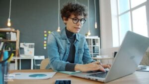 Woman at her laptop learning about how to get her real estate license with a step by step guide.