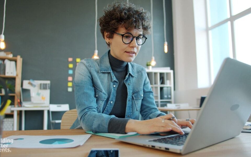 Woman at her laptop learning about how to get her real estate license with a step by step guide.